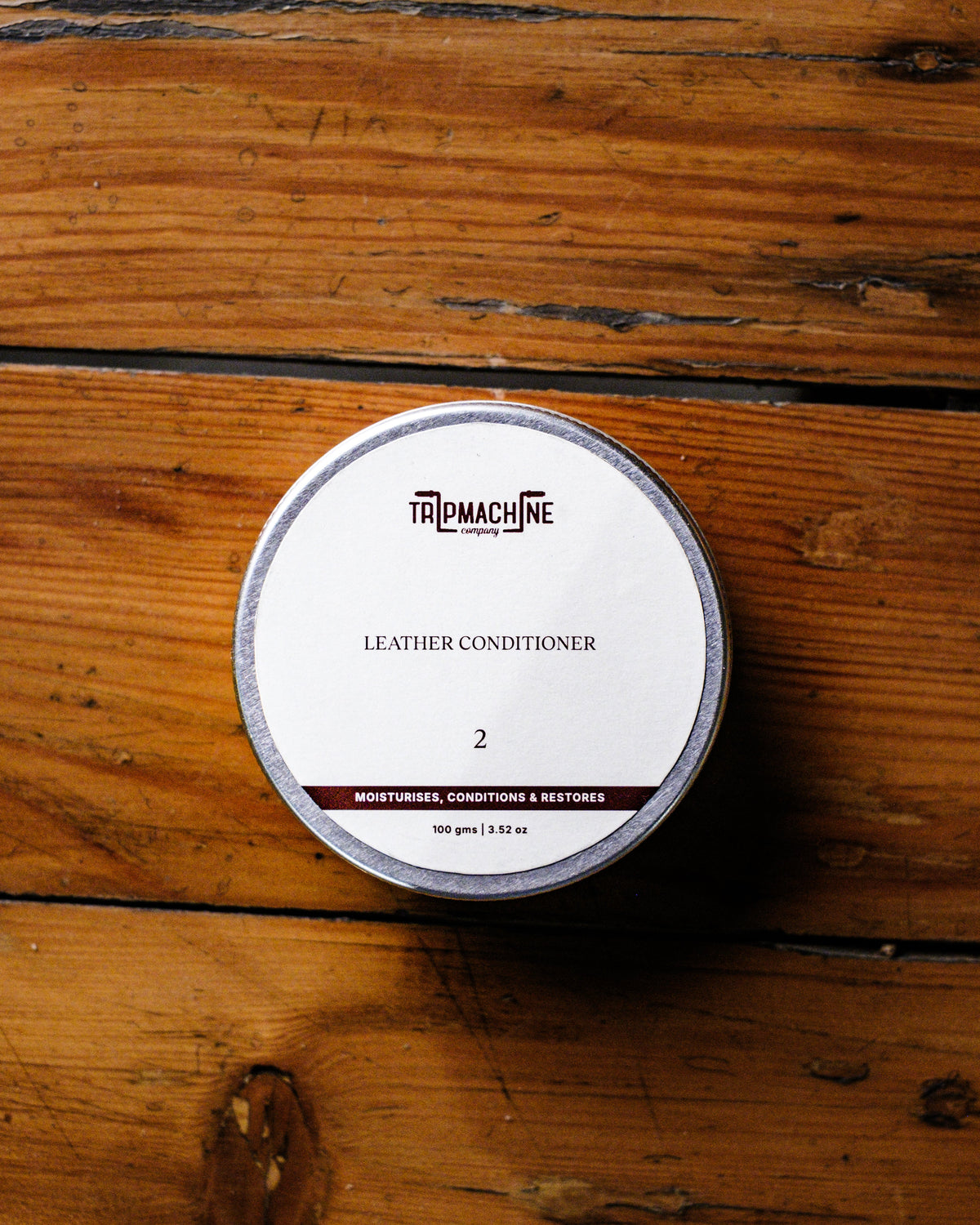 Tripmachine leather conditioner container on a wooden surface